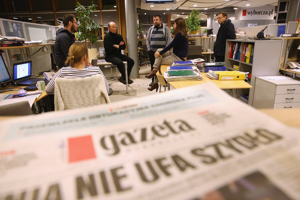 WARSAW, POLAND - FEBRUARY 26:  Piotr Stasinski (C-L, in black), Deputy Editor-in-Chief of Polish independent daily newspaper Gazeta Wyborcza, speaks with editorial colleagues in the newsroom of the paper near a copy of Gazeta Wyborcza whose headline reads: "The EU Distrusts Szydlo", in reference to new Polish Prime Minister Beata Szydlo, on February 26, 2016 in Warsaw, Poland. Independent media in Poland currently face a new, uncertain political atmosphere with the conservative and populist Law and Justice (PiS) political party, led by Jaroslaw Kaczynski, having won elections last year and appointing President Andrzej Duda and Prime Minister Beata Szydlo. Since taking office PiS legislators have curtailed the power of the Constitutional Court and removed critical journalists from state-owned media. Stasinski says critics charge Gazeta Wyborcza is too anti-PiS and hence too partisan, though he says the paper's strident role is crucial in defending democracy in Poland under the new government.  (Photo by Sean Gallup/Getty Images)