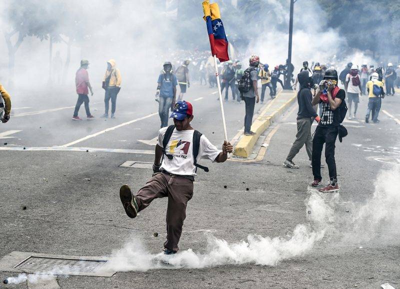 A demonstrator kick a tear gas canister back at riot police during a protest against President Nicolas Maduro, in Caracas on May 8, 2017.Venezuela's opposition mobilized Monday in fresh street protests against President Nicolas Maduro's efforts to reform the constitution in a deadly political crisis. Supporters of the opposition Democratic Unity Roundtable (MUD) gathered in eastern Caracas to march to the education ministry under the slogan "No to the dictatorship." / AFP PHOTO / JUAN BARRETO