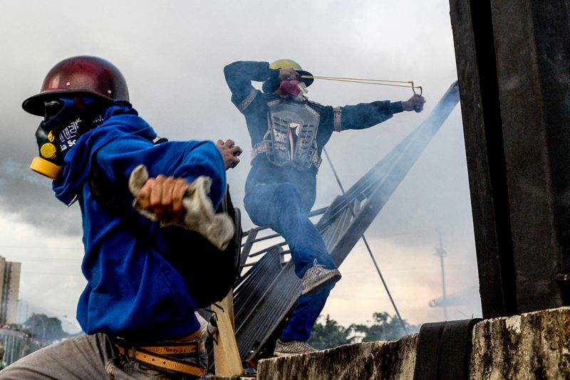 Opposition activists and riot police clash during a protest against President Nicolas Maduro, in Caracas on May 8, 2017.Venezuela's opposition mobilized Monday in fresh street protests against President Nicolas Maduro's efforts to reform the constitution in a deadly political crisis. Supporters of the opposition Democratic Unity Roundtable (MUD) gathered in eastern Caracas to march to the education ministry under the slogan "No to the dictatorship." / AFP PHOTO / FEDERICO PARRA