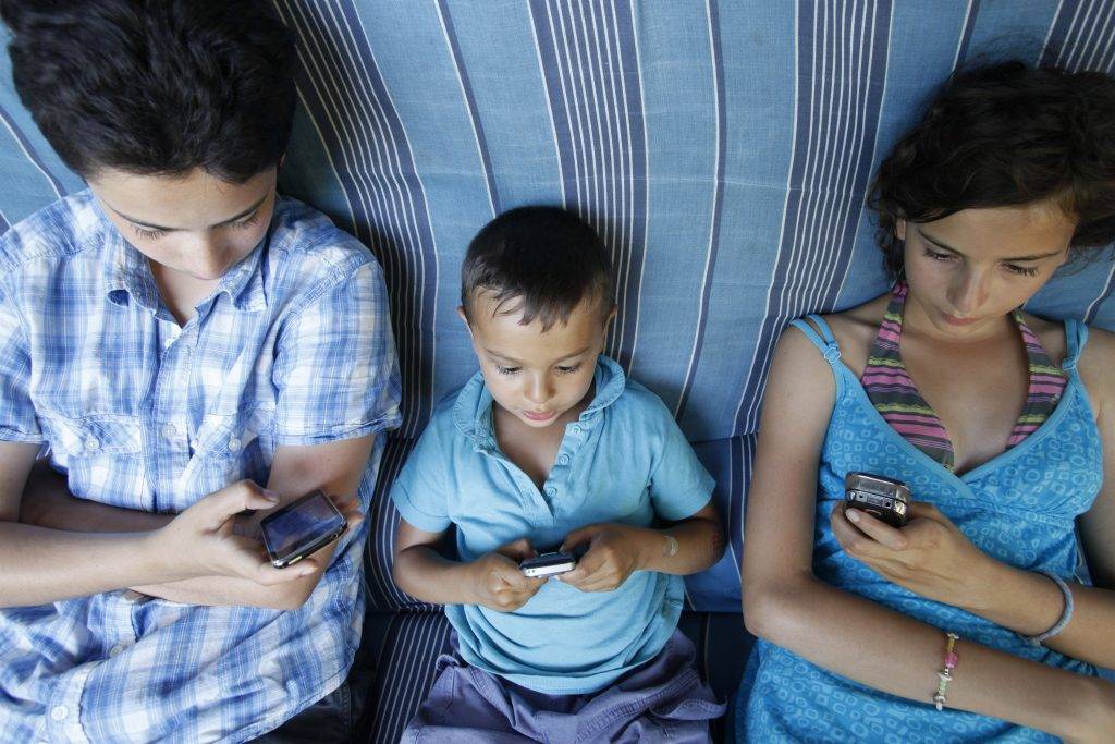 Children playing games on mobile phones France. - France, Gironde, Hourtin