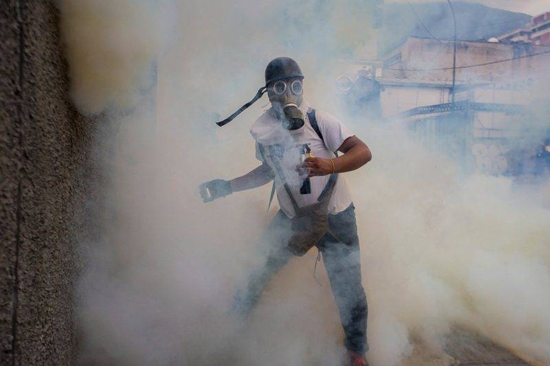 Caracas, 2017. április 11.Egy gázálarcot viselő tüntető kezében egy könnygázgránáttal a Nicolás Maduro elnök vezette szocialista kormány elleni tüntetésen Caracasban 2017. április 10-én. (MTI/EPA/Miguel Gutierrrez)