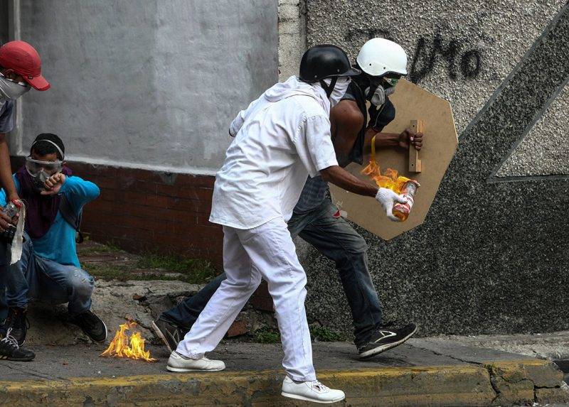 Caracas, 2017. május 4.Molotov-koktélt dob egy tüntető nemzeti gárdisták felé a Nicolás Maduro venezuelai elnök és szocialista kormánya elleni tiltakozáson Caracasban 2017. május 3-án. Az erőszakba torkollt újabb tüntetésen életét vesztette egy tizenhét éves fiatal, több mint kétszázan megsérültek. (MTI/EPA/Christian Hernández)