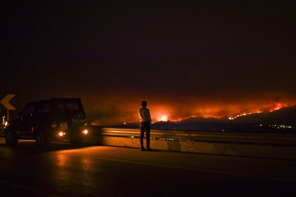 A man stands on the roadside watching a wildfire at Anciao, Leiria, central Portugal, on June 18, 2017. 
A wildfire in central Portugal killed at least 25 people and injured 16 others, most of them burning to death in their cars, the government said on June 18, 2017. Several hundred firefighters and 160 vehicles were dispatched late on June 17 to tackle the blaze, which broke out in the afternoon in the municipality of Pedrogao Grande before spreading fast across several fronts.    / AFP PHOTO / PATRICIA DE MELO MOREIRA