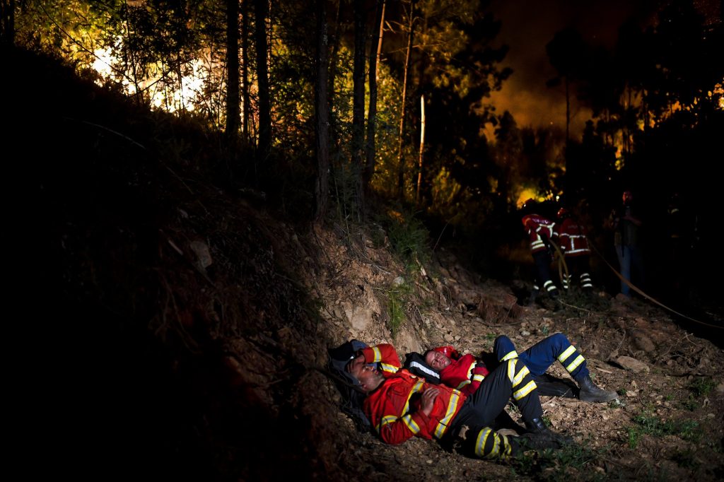 Firefighters rest during a wildfire at Penela, Coimbra, central Portugal, on June 18, 2017. 
A wildfire in central Portugal killed at least 25 people and injured 16 others, most of them burning to death in their cars, the government said on June 18, 2017. Several hundred firefighters and 160 vehicles were dispatched late on June 17 to tackle the blaze, which broke out in the afternoon in the municipality of Pedrogao Grande before spreading fast across several fronts.  / AFP PHOTO / PATRICIA DE MELO MOREIRA