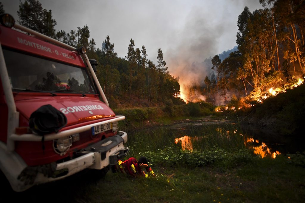 A firefighter rests next to fire combat truck during a wildfire at Penela, Coimbra, central Portugal, on June 18, 2017. 
A wildfire in central Portugal killed at least 25 people and injured 16 others, most of them burning to death in their cars, the government said on June 18, 2017. Several hundred firefighters and 160 vehicles were dispatched late on June 17 to tackle the blaze, which broke out in the afternoon in the municipality of Pedrogao Grande before spreading fast across several fronts.    / AFP PHOTO / PATRICIA DE MELO MOREIRA