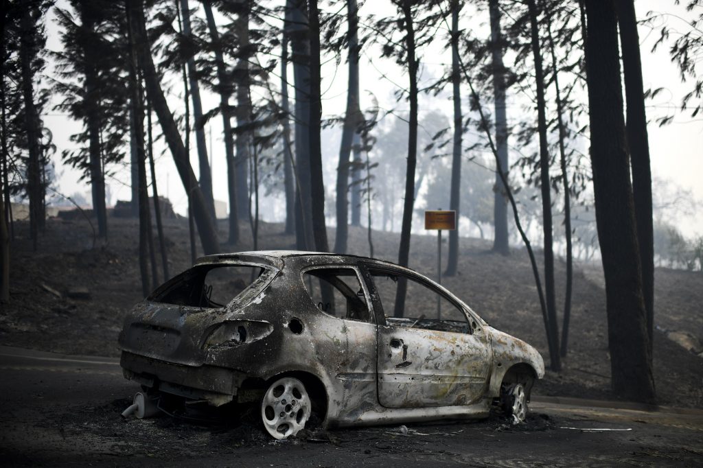 A picture taken on June 18, 2017 shows a burnt car on a road after a wildfire in Pedrogao, in central Portugal.
A wildfire in central Portugal killed at least 57 people and injured 59 others, most of them burning to death in their cars, the government said on June 18, 2017. Several hundred firefighters and 160 vehicles were dispatched late on June 17 to tackle the blaze, which broke out in the afternoon in the municipality of Pedrogao Grande before spreading fast across several fronts.    / AFP PHOTO / PATRICIA DE MELO MOREIRA