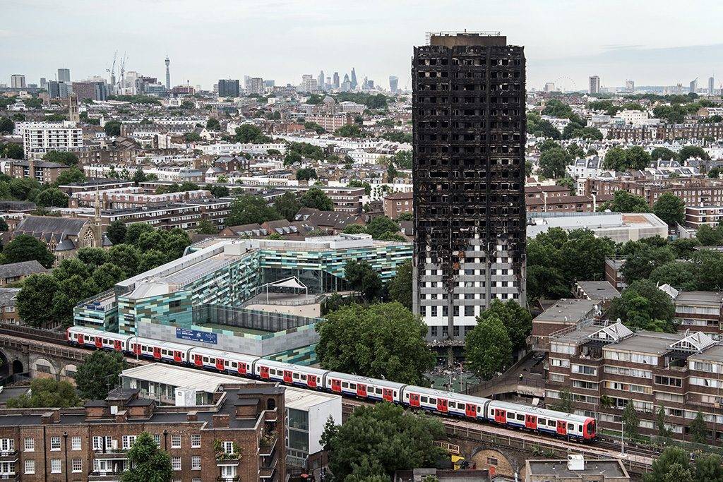 LONDON, ENGLAND - JUNE 26:  A tube train passes the remains of Grenfell Tower, seen from a neighbouring tower block on June 26, 2017 in London, England. 79 people have been confirmed dead and dozens still missing after the 24 storey residential Grenfell Tower block was engulfed in flames in the early hours of June 14, 2017.  (Photo by Carl Court/Getty Images)