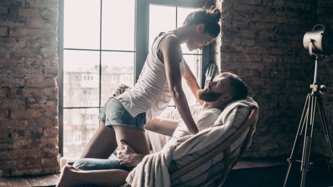 Young passionate couple looking on each other while spending free time at home
