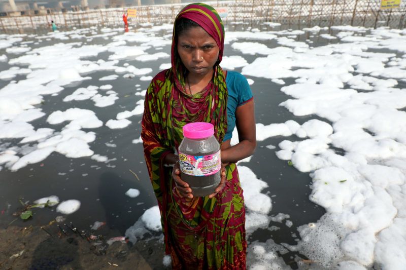 Újdelhi, 2018. január 9.A 2018. január 9-én közreadott képen egy hindu rituáléhoz készülő indiai nő a vegyszerhabbal borított Jamuna folyóból merített vizet tartja tégelyében Újdelhiben 2017. október 24-én. A Himalája Jamunotri-gleccserének kristálytiszta olvadékvizéből eredő folyó az indiai fővároson keresztül Uttar Prades szövetségi államban ömlik a Gangeszbe. Mindkét folyót vallásos tisztelet övezi, mivel a hinduk hite szerint a szent vizekben való megmártózás megszabadít a halál gyötrelmeitől. (MTI/EPA/Haris Tjagi)