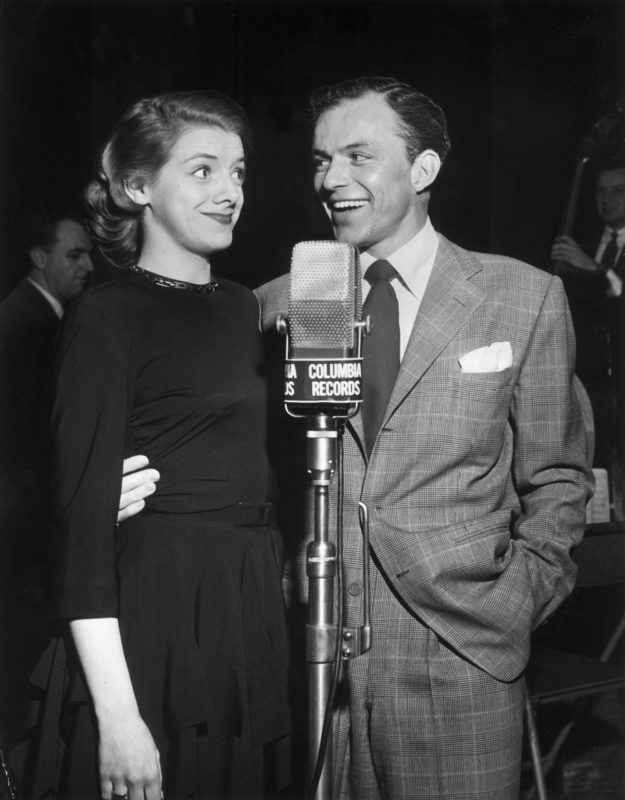 circa 1950:  American actors and singers Rosemary Clooney (1928 - 2002) and Frank Sinatra stand together in front of a Columbia Records microphone. Sinatra is smiling and has his arm around Clooney.  (Photo by Hulton Archive/Getty Images)