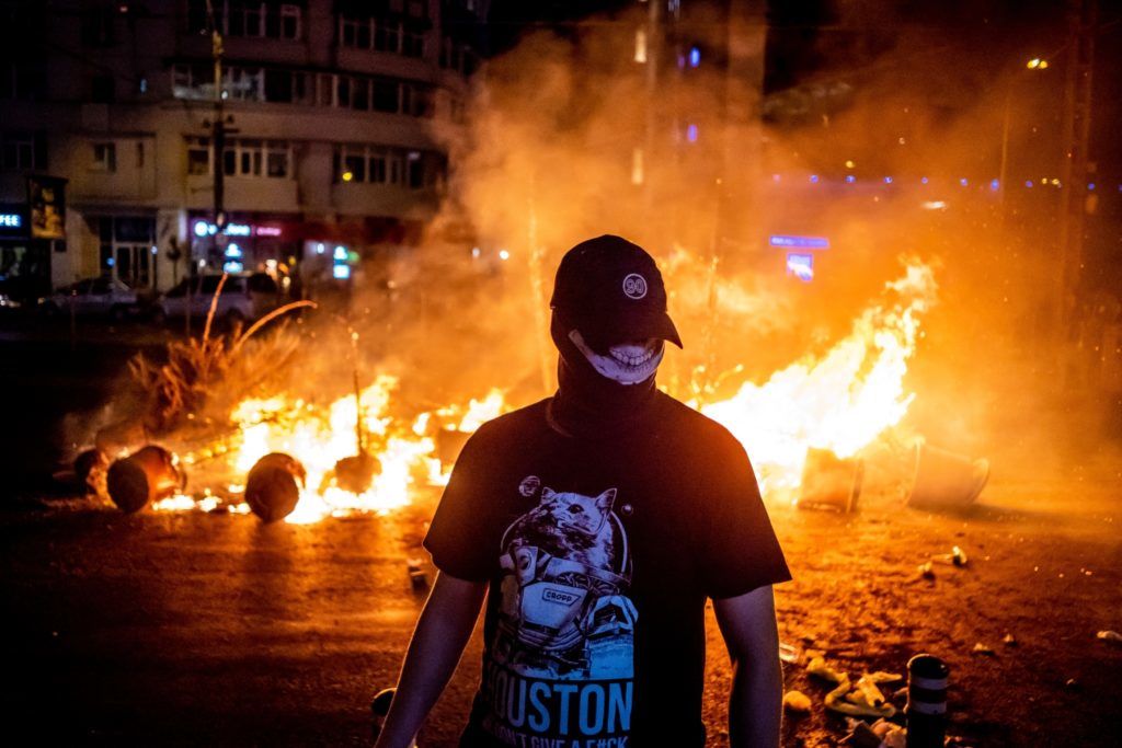 A protester walks past a fire during clashes with police at a demonstration against the government in front of the Romanian Government headquarters, in Bucharest August 10, 2018. 
Romanian police used water cannon and tear gas to disperse anti-corruption protesters in Bucharest after tens of thousands rallied to call on the leftwing government to resign. Local media said between 50,000 to 80,000 people turned out for the protest, including many Romanian expatriates who returned home to show their anger at the graft in one of the EU's most corruption-plagued members.
 / AFP PHOTO / Andrei PUNGOVSCHI