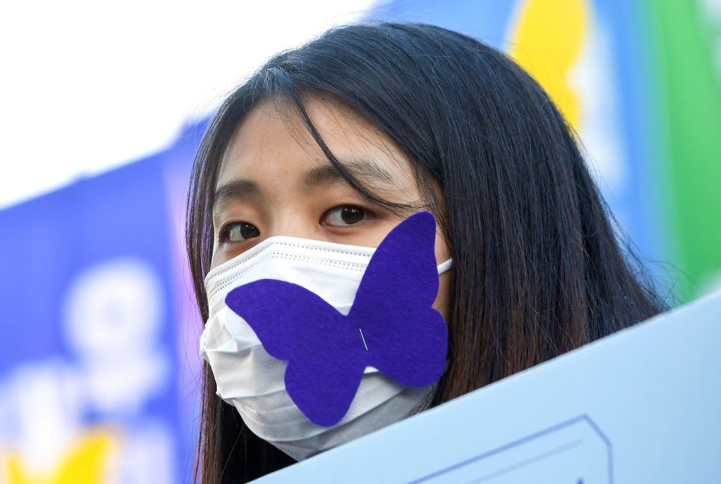 A mourner wears a face mask with a paper cutout of butterfly, symbols of sexual slavery victims, during a funeral ceremony of former South Korean "comfort woman" Kim Bok-dong, who was forced to serve as a sex slave for Japanese troops during World War II, near the Japanese embassy in Seoul on February 1, 2019. - Kim Bok-dong was a symbolic figure for weekly rallies in front of the Japanese embassy in Seoul that started in 1992, demanding a full, heart-felt apology from Tokyo. (Photo by Jung Yeon-je / AFP)