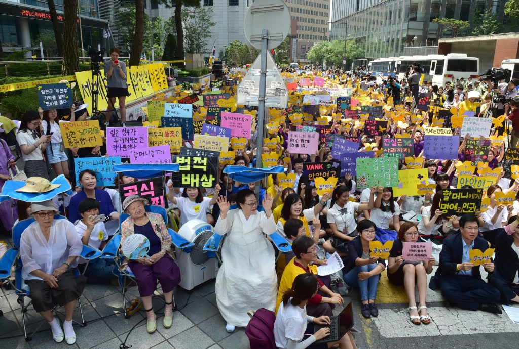 (L-R on blue chairs) South Korean former "comfort women" Kim Bok-Dong, Gil Won-Ok and Lee Yong-Soo, who were forced to serve as sex slaves for Japanese troops during World War II, attend a protest with other supporters to demand Tokyo's apology for forcing women into military brothels during World War II outside the Japanese embassy in Seoul on August 12, 2015. Close to 1,000 protestors had gathered outside the embassy ahead of the 70th anniversary of the end of Japan's 1910-45 colonial rule over the Korean peninsula.  AFP PHOTO / JUNG YEON-JE (Photo by JUNG YEON-JE / AFP)