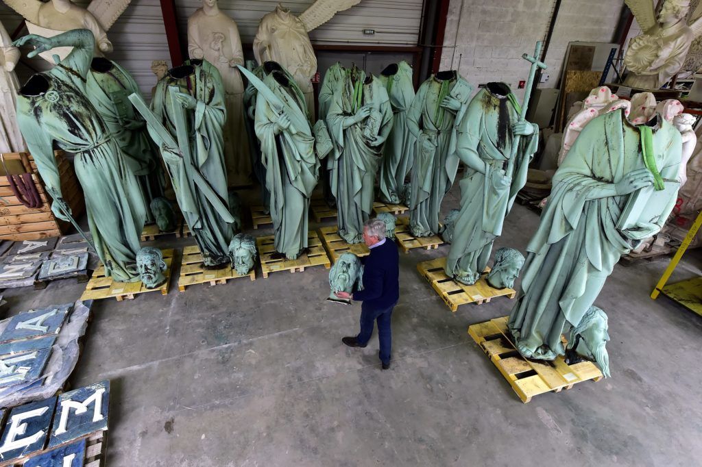 Patrick Palem, expert of the heritage restoration, walks by the statues which sat around the spire of the Notre-Dame cathedral in Paris and removed for restoration, stored in SOCRA workshop in Marsac-sur-Isle near Bordeaux, on April 16, 2019. - Paris was struck in its very heart as flames devoured the roof of Notre-Dame cathedral, causing a spire to collapse and raising fears over the future of the nearly millenium old building and its precious artworks. The sixteen statues which sitted around the spire of the cathedral, 12 apostles and the 4 evangelists commisioned in the 1860s during the great restoration of the cathedral by Viollet-le-Duc, have been removed in April to be sent in southwest France for restoration. (Photo by GEORGES GOBET / AFP)