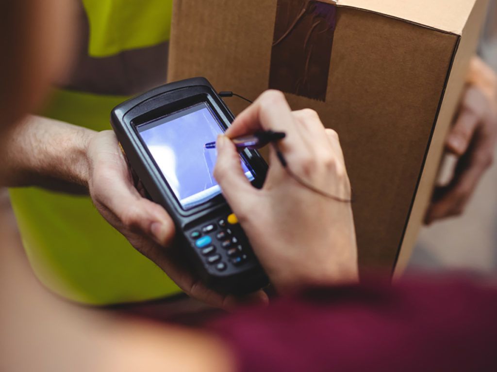 Woman signing on device to delivery parcel by van