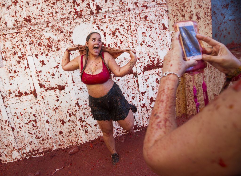 A reveller covered in tomato pulp poses for a picture during the annual "Tomatina" festival in the eastern town of Bunol, on August 28, 2019. - The iconic fiesta, which is billed at "the world's biggest food fight" has become a major draw for foreigners, in particular from Britain, Japan and the United States. (Photo by JAIME REINA / AFP)