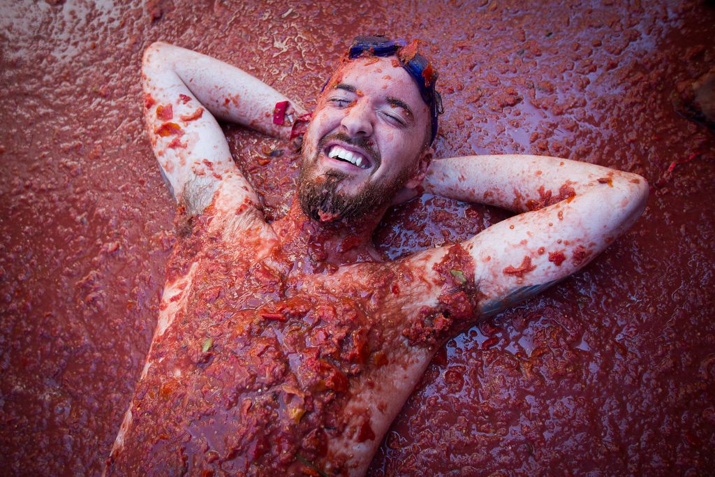 A reveller covered in tomato pulp takes part in the annual "Tomatina" festival in the eastern town of Bunol, on August 28, 2019. - The iconic fiesta, which is billed at "the world's biggest food fight" has become a major draw for foreigners, in particular from Britain, Japan and the United States. (Photo by JAIME REINA / AFP)