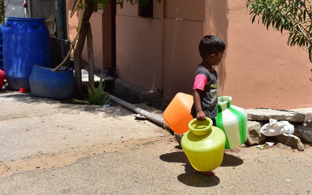 A small boy walks with three empty pots to help his mother fill water from a water tanker near Ondipudur in Coimbatore, on June 13, 2019. The Times of India/J Jackson
