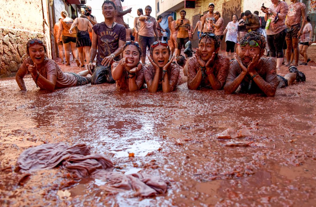 5988995 28.08.2019 People pose for a photo lying in the tomato pulp during the annual "La Tomatina" tomato food fight festival in Bunol, outside Valencia, Spain. Every year on the last Wednesday of August tens of thousands of people throw tomatoes and get involved in a tomato fight as more than one hundred metric tons of over-ripe tomatoes are thrown in the streets of Bunol. Carolina Cabral / Sputnik