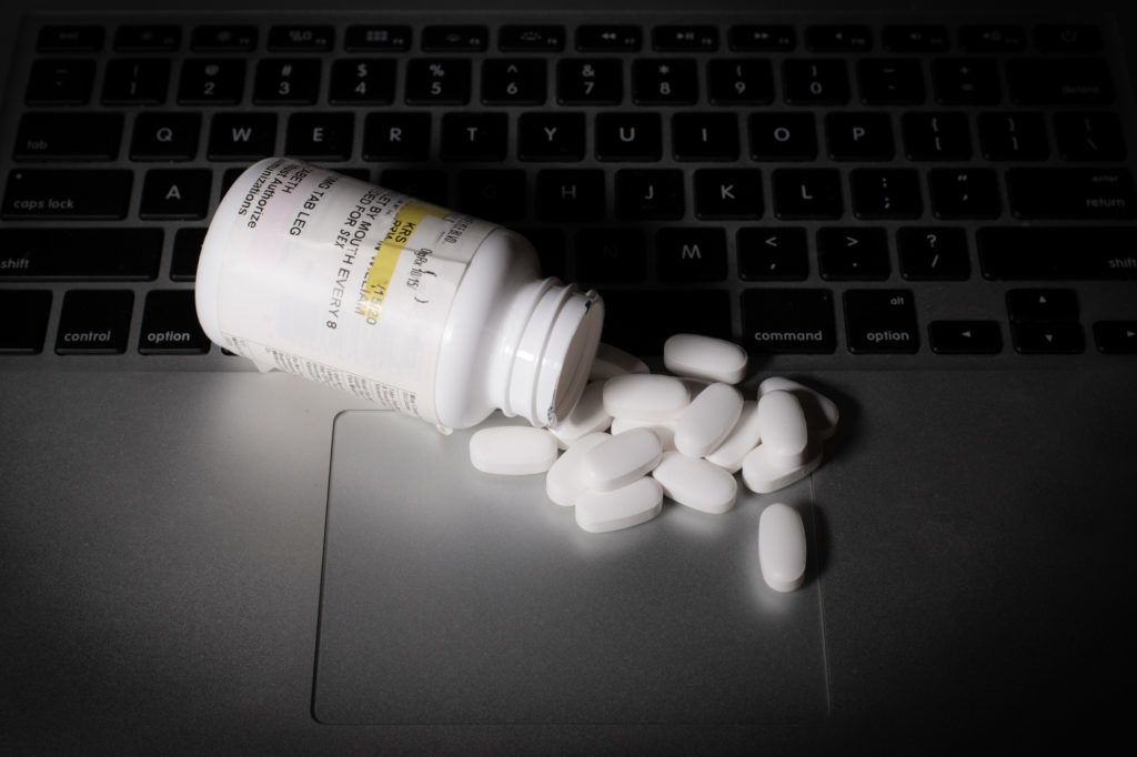 Prescription medication is strewn atop of a laptop keyboard.